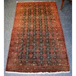 A Baluchi rug, with allover red floral designs on navy ground, with red geometric border,