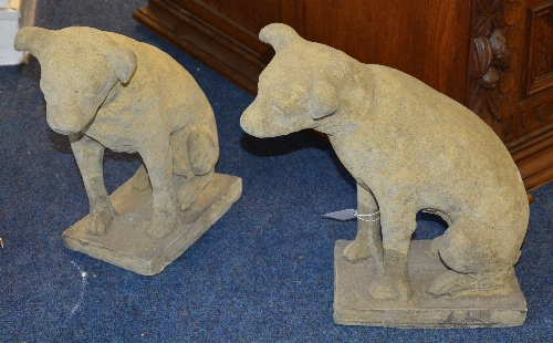 A pair of composite stone dog figures, raised on plinths,