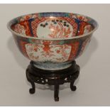 A 20th century Japanese Imari bowl on carved wood stand,