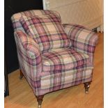 A tartan upholstered armchair, raised on turned mahogany supports with brass castors,