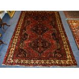 WITHDRAWN - An Iranian rug, decorated with three central motifs on blue and deep red ground,