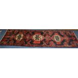 A Hamadan runner, the three central diamond motifs over red ground with navy border,