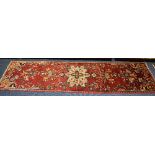 A Hamadan runner, the central cream flowerhead motif over red ground,