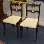 A pair of Regency style mahogany dining chairs, with drop in seats and raised on sabre supports,