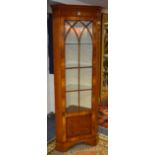 A reproduction yew wood corner cabinet, with glazed door enclosing glass shelves,