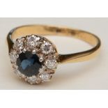 A sapphire and diamond cluster ring, set with central round cut sapphire to centre,