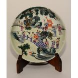 A Chinese famille rose circular dish, decorated with panel of figures and trees in typical colours,