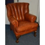 A Chippendale style contemporary brown leather armchair, raised on ball and claw supports,