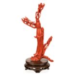 A CHINESE CARVED RED CORAL FIGURE OF A GUANYIN POURING HEALING WATER