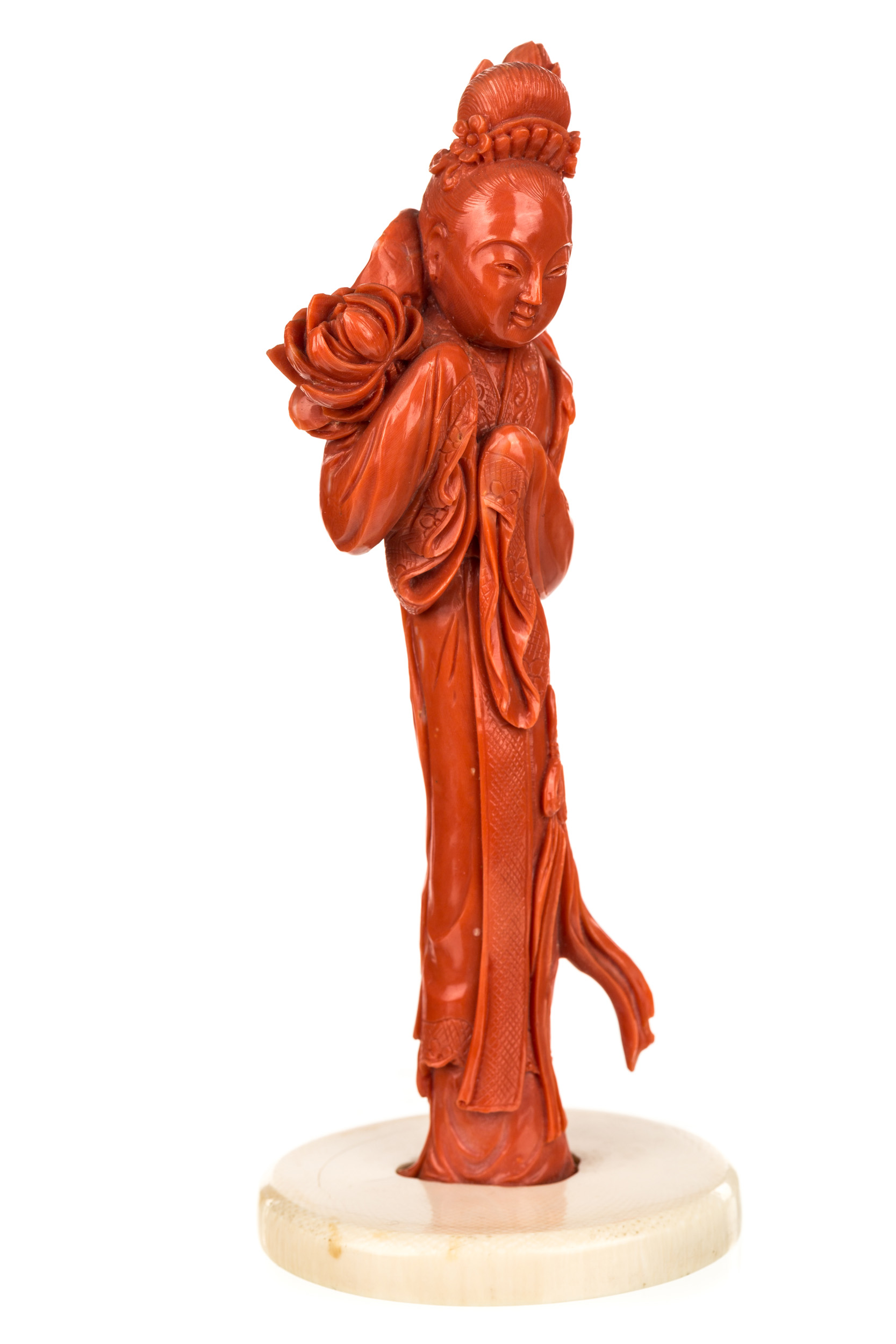 A CHINESE CARVED RED CORAL FIGURE OF A GUANYIN HOLDING A LOTUS