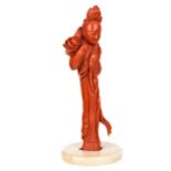 A CHINESE CARVED RED CORAL FIGURE OF A GUANYIN HOLDING A LOTUS