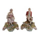 PAIR OF GERMAN PORCELAIN FIGURE MOUNTED CANDLE HOLDERS each raised on a flower encrusted mound 26