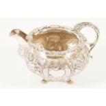 SILVER CRESTED CREAM JUG with mask headed scroll handle and ornate spout. The body chased and