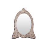 SILVER FRAMED VANITY MIRROR with embossed leaf scroll decoration 31 cm. high; 25 cm. wide