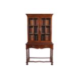 ANTIQUE WALNUT CABINET-ON-STAND the superstructure with a moulded crown above square glazed doors,