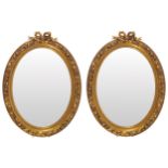 PAIR OF EARLY TWENTIETH CENTURY GILT FRAMED PIER MIRRORS each with an oval plate, within a ribbon