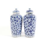 PAIR OF CHINESE QING PERIOD BLUE AND WHITE URNS AND COVERS each with all over floral and leaf