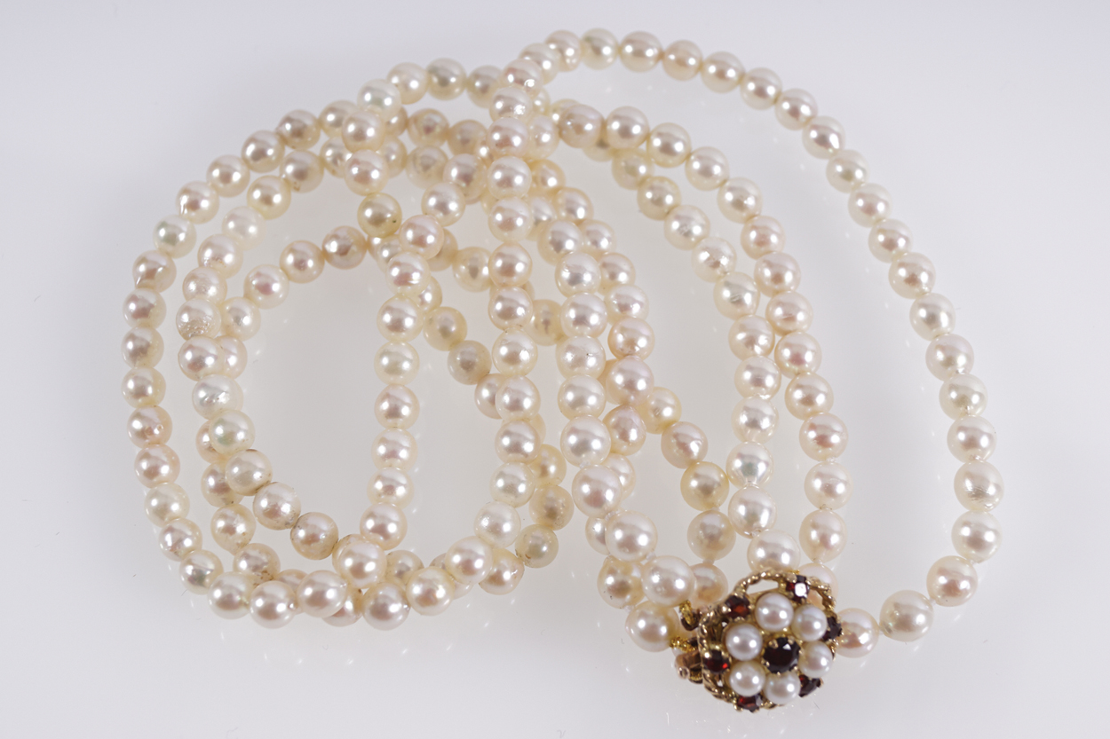 THREE STRAND CULTURED PEARLS with garnet and pearl clasp