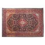 KASHAN WOOL RUG, CIRCA 1930 navy ground, silk centre, cartouches, red border 142 x 219 cm.