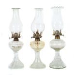 3 Petroleum-Lampen Portugal, um 1900/20, klares Pressglas, davon 1 Paar mit Fischen dekorierter