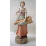 An Austrian porcelain figure of a peasant girl carrying a sickle and a sheaf of wheat, blush