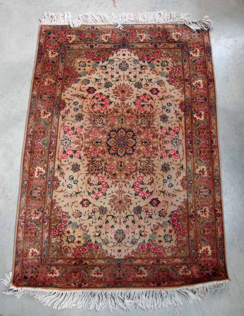 A Middle Eastern silk and wool rug, having a central field of foliate design incorporating flower