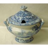 A large stoneware two-handled tureen of circular form, blue and white, decorated with a view of