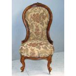 A Victorian upholstered nursing chair with carved walnut frame and moulded and carved knop feet