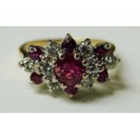 An 18ct gold ruby and diamond cluster ring, a central ruby surrounded geometrically by eight