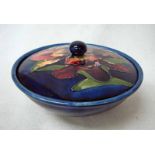 A Walter Moorcroft lidded bowl of circular form tubeline decorated in the Orchid design on deep blue