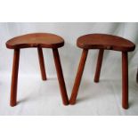 A pair of oak milking stools by Robert 'Mouseman' Thompson of Kilburn, three legged with kidney