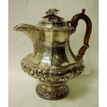 A George IV Regency silver water jug of compressed baluster form, embossed with foliage and fruit,