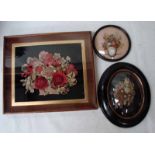 A cut fabric diorama still life of flowers in a basket on a black background in a rectangular frame,