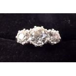 A platinum ring set three diamonds, the centre stone approx one carat flanked by two half carat
