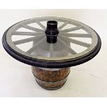 A wagon wheel and glass topped coffee table raised on barrel base 77cm diameter