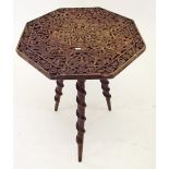 A South East Asian occasional table, the top carved with depictions of Buddha and the three legs