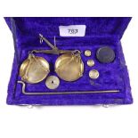 A set of gold scales and weights, cased