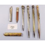 Five silver plated pencils, a silver pencil holder and a gilt metal one