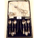 A matched set of six silver teaspoons and tongs, a pair of silver plated grape scissors, a napkin