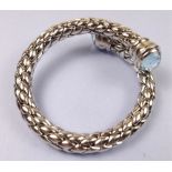 A woven silver bangle with blue topaz set terminals