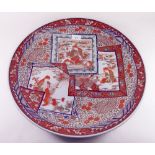 A large Japanese 19th century Imari charger with panels decorated seated craftsmen