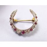 An 18 carat white and yellow gold crescent brooch set rubies and diamonds