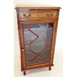 An Edwardian mahogany music cabinet with chevron stringing, the frieze drawer over glazed door