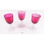 A set of three Victorian cranberry wine glasses with faceted stems