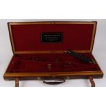 Oak and leather brass mounted double gun case, the claret tone baize lined fitted interior with