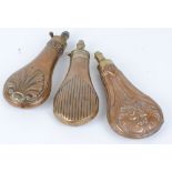 Three copper and brass powder flasks with embossed shell, scroll and fluted decoration by Ward,