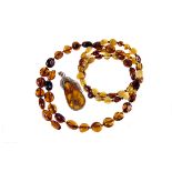 A group of amber jewellery, including a wire strung coil choker and bracelet, and a pebble