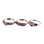 A gold, silver and amethyst dress ring,  the three graduated stones with gold stitch detailing,