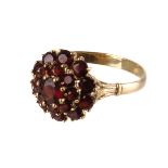 An garnet cluster ring,  the three tiered bezel to engraved trifurcated shoulders, the 18ct gold