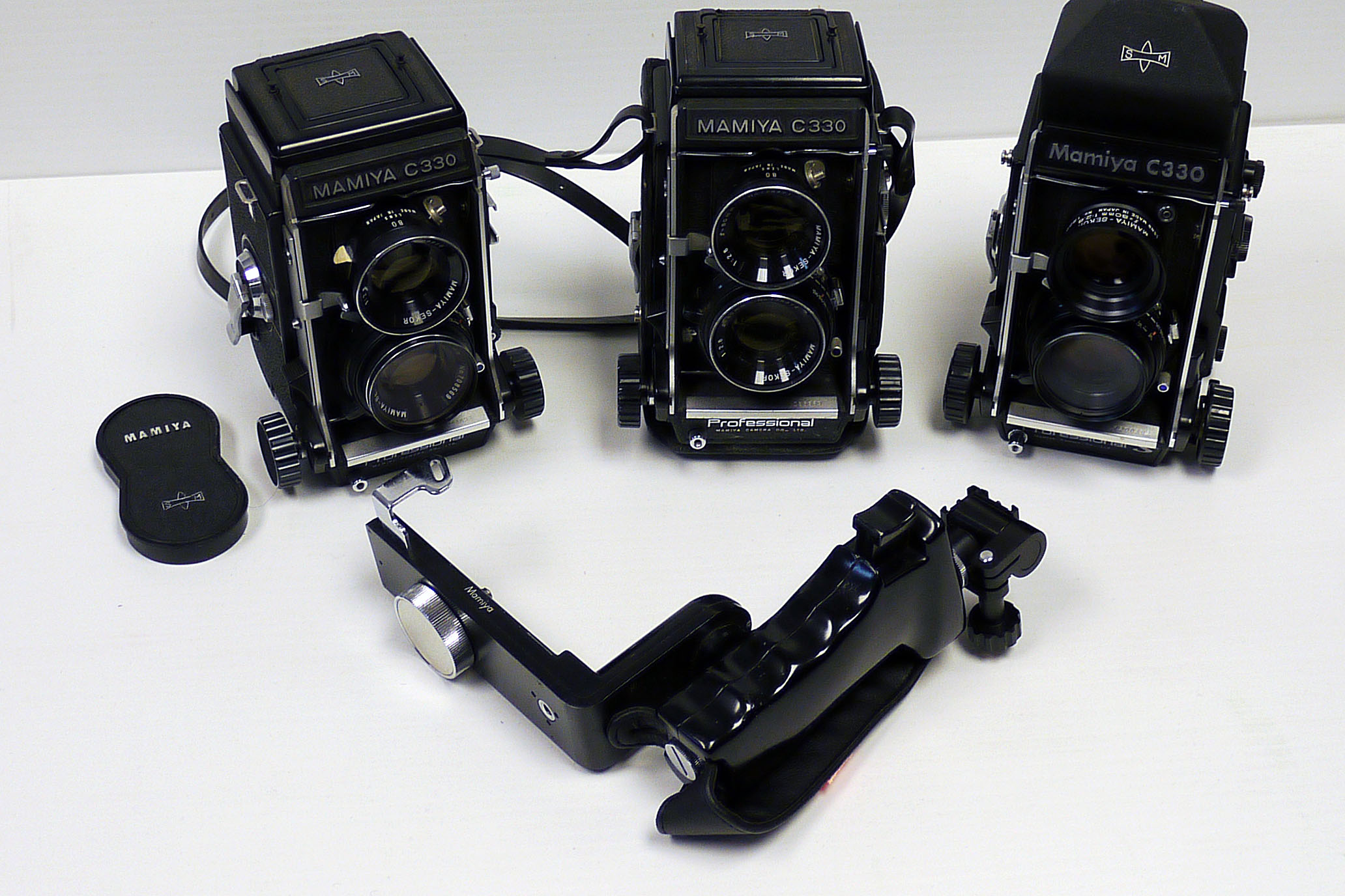 Mamiya C330 Cameras: three examples with 80mm lenses also a prism finder and Mamiya side grip (a